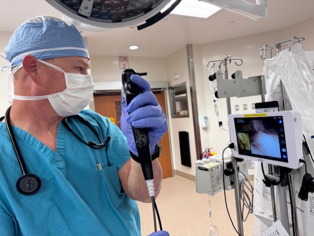 Doctor holding scope device while looking at screen in an operating room